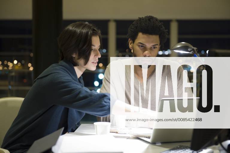 Colleagues working on project together in office at night