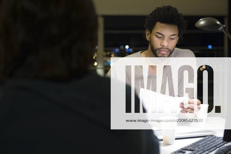 Colleagues working on project together in office at night