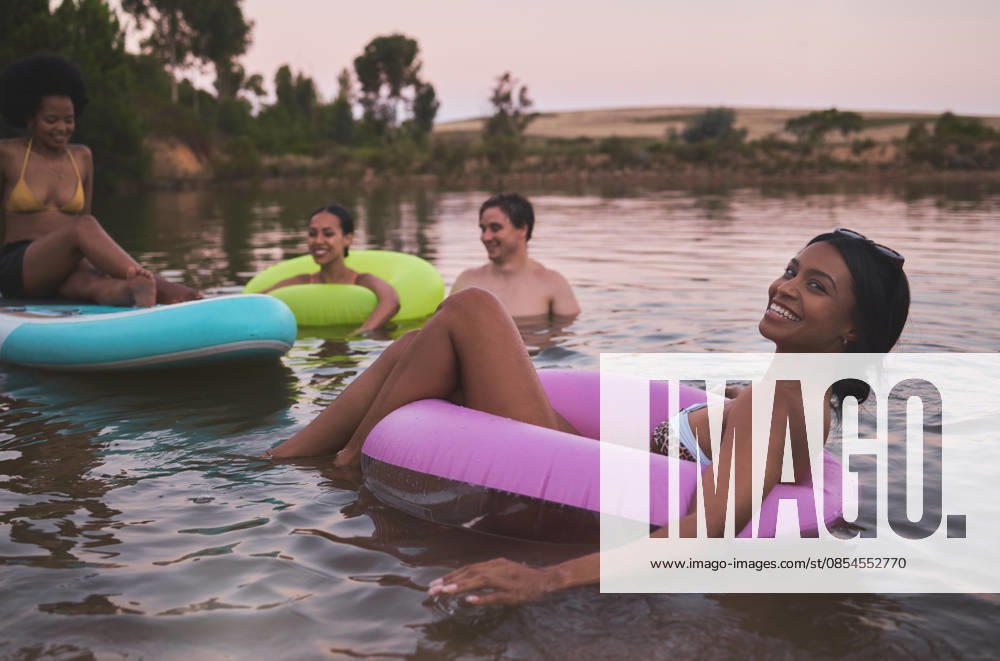 Vacation, swimming and friendship having fun in a lake while enjoying the summer sunset. Happy friends relaxing and floating in water while talking and bonding on a getaway holiday. (License=RF) ,model released, Symbolfoto