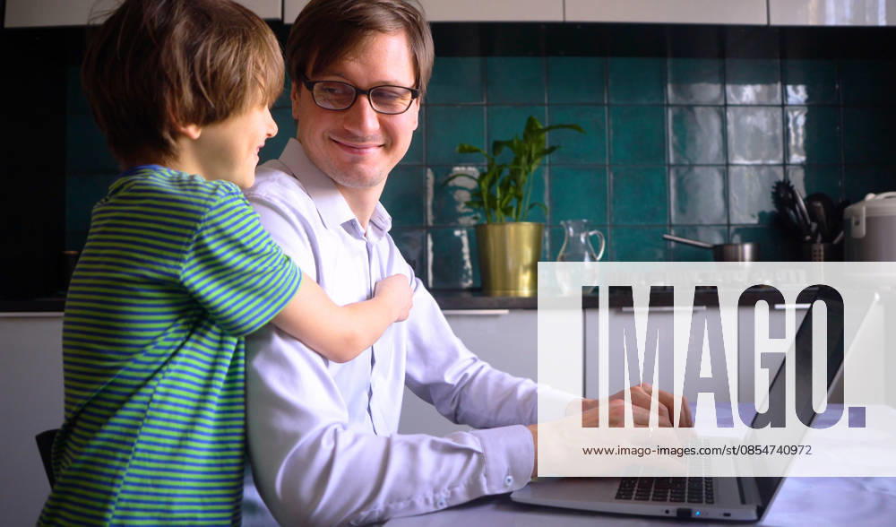 Ein junger Mann arbeitet mit seinem Sohn an einem Laptop in der Küche. Homeoffice mit Kindern. Young man working in the kitchen at a laptop with his a son. Home office with kids. Concept for remote work at home during the coronavirus quarantine period Covid 19. (License=RF) ,model released, Symbolfoto