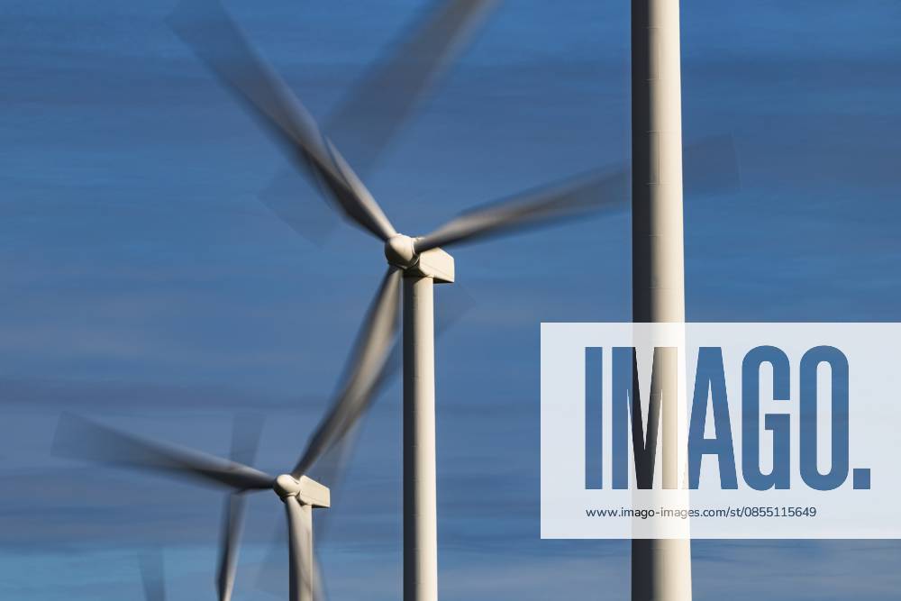 Eine Reihe sich drehender, rotierender Windräder mit Bewegungsunschärfe vor blauem Himmel mit Wolken, Langzeitbelichtung, Windkraft, Windenergie, erneuerbare Energie, Schagen, Nordholland, Niederlande A series of spinning, rotating wind turbines with motion blur against a blue sky with clouds, long exposure, wind power, wind energy, renewable energy, Schagen, North Holland, the Netherlands