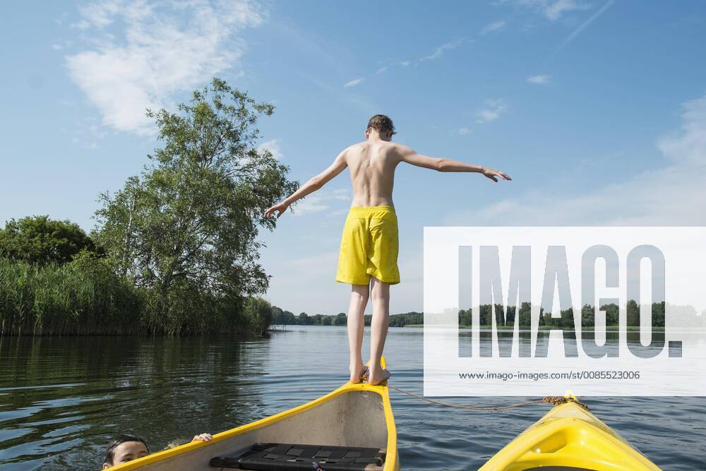 Rear view of boy jumping from canoe in lake