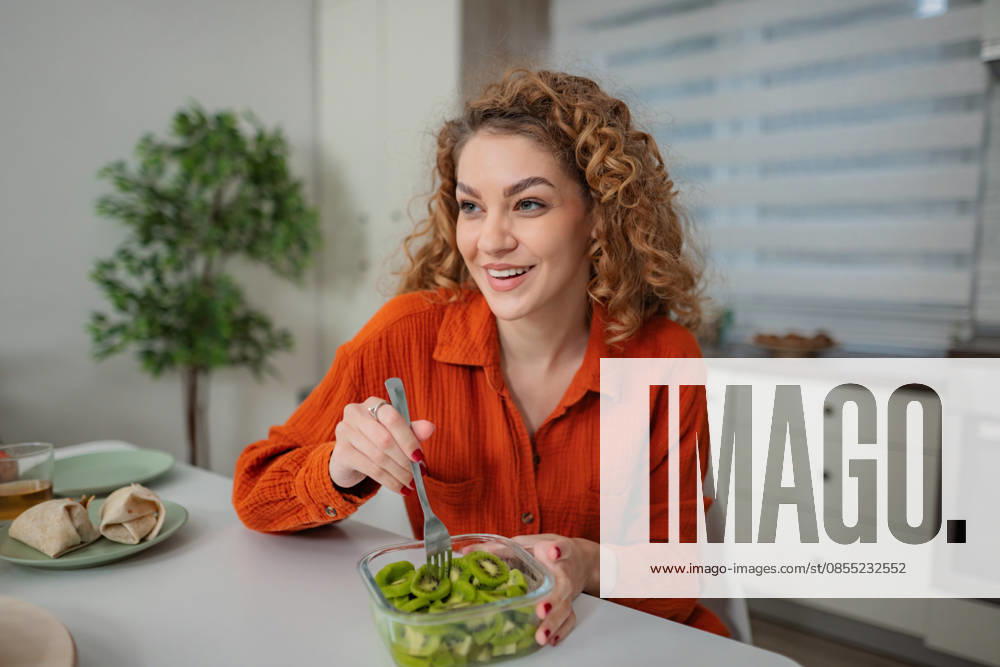 Eine Frau genießt in der Küche ein gesundes Frühstück mit Kiwis Eine Frau genießt in der Küche ein gesundes Frühstück mit Kiwis (License=RF) ,model released, Symbolfoto
