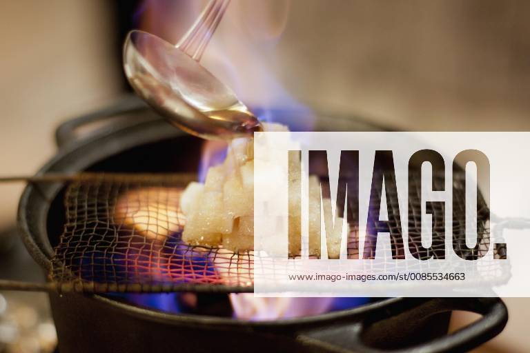 Close-up of rum is being poured on sugar cubes while preparing Feuerzangenbowle
