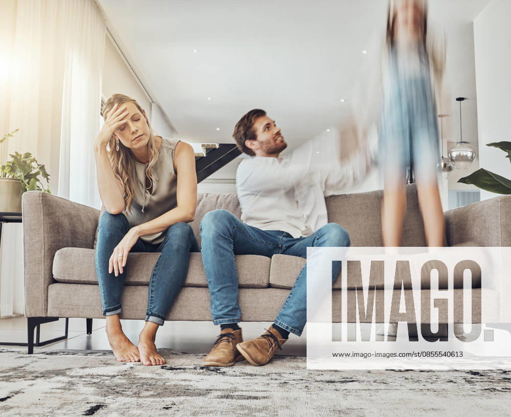 Family life stress, parents and child, chaos at home and energy, motion blur and burnout headache. Kid jump on couch, woman has migraine and man calming girl, hyperactive with ADHD and mental health. (License=RF) ,model released, Symbolfoto