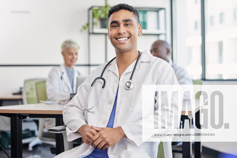 Young doctor, man and portrait at hospital desk with smile for healthcare, planning and teamwork. Professional leader, doctors and expert in health, wellness and happy in clinic with group at table. (License=RF) ,model released, Symbolfoto