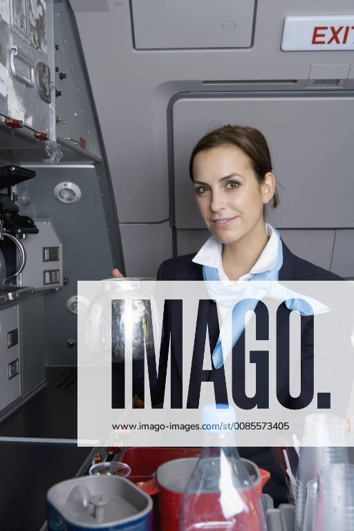 A flight attendant holding a coffee pot in an airplane galley