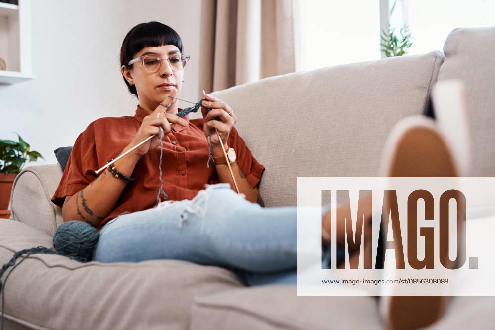 Relax, woman and knitting in living room for craft, hobby and creative in home for fashion. Designer, female person and sewing or crochet on weekend in apartment with yarn, pride and cotton on sofa. (License=RF) ,model released, Symbolfoto