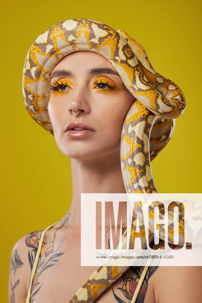 Woman, snake or thinking with beauty in studio for fashion or makeup cosmetics on a yellow background. Thoughtful, female person or aesthetic with eye shadow, reptile animal or serpent for style. model released property released