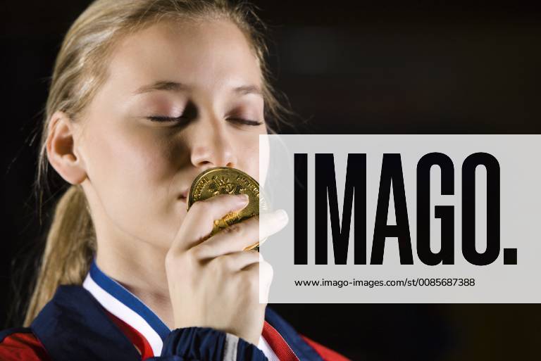 IMAGO Creative: Internationaler Frauenmonat, Mädchen im Sport Female athlete kissing gold medal, portrait