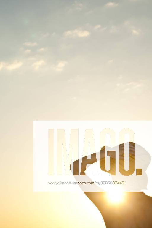 IMAGO Creative, Jahreszeit Sommer, Sonnenschutz Woman outdoors silhouetted against setting sun
