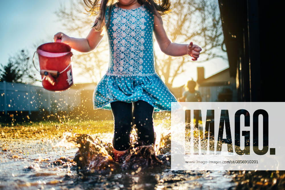 IMAGO Creative, Jahreszeit Sommer, Regen, Sommerregen Girl Jumping in Rain Puddle with Backlight Oklahoma City, Oklahoma, United States CR_KRRY260517-2015303-01 ,model released, Symbolfoto