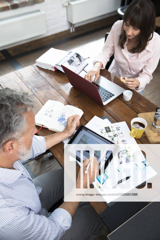 Mature couple working from their home office, using laptop and digital tablet model released Symbolfoto property released FKF03069