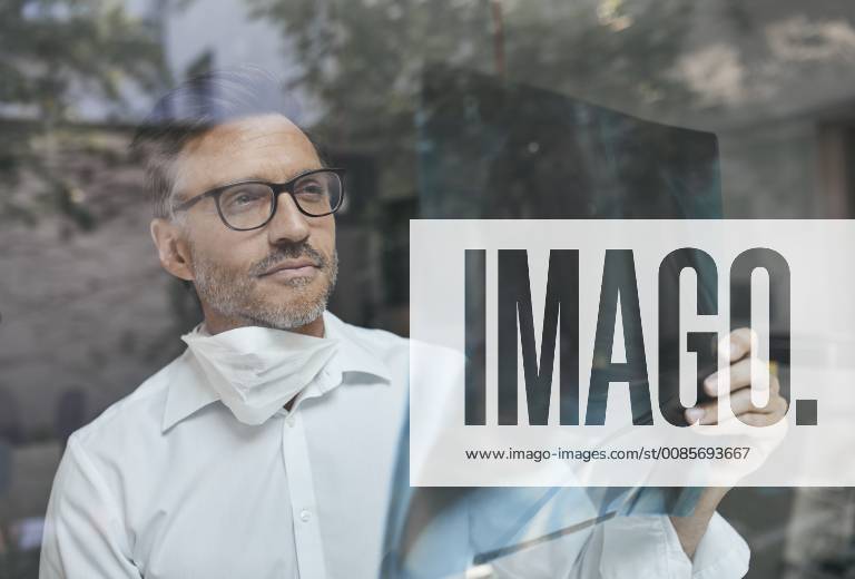 Portrait of radiologist behind windowpane looking at x-ray image model released Symbolfoto PNEF00820