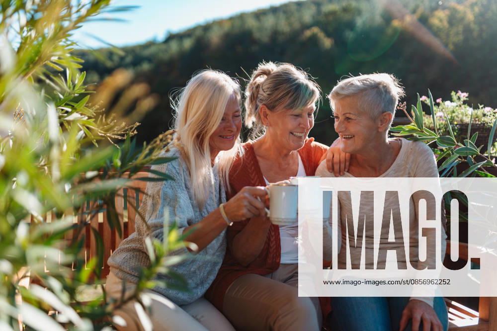 Senior female friends enjoying coffee together on cabin terrace getaway. Older female friends enjoying coffee together on cabin terrace getaway. model released