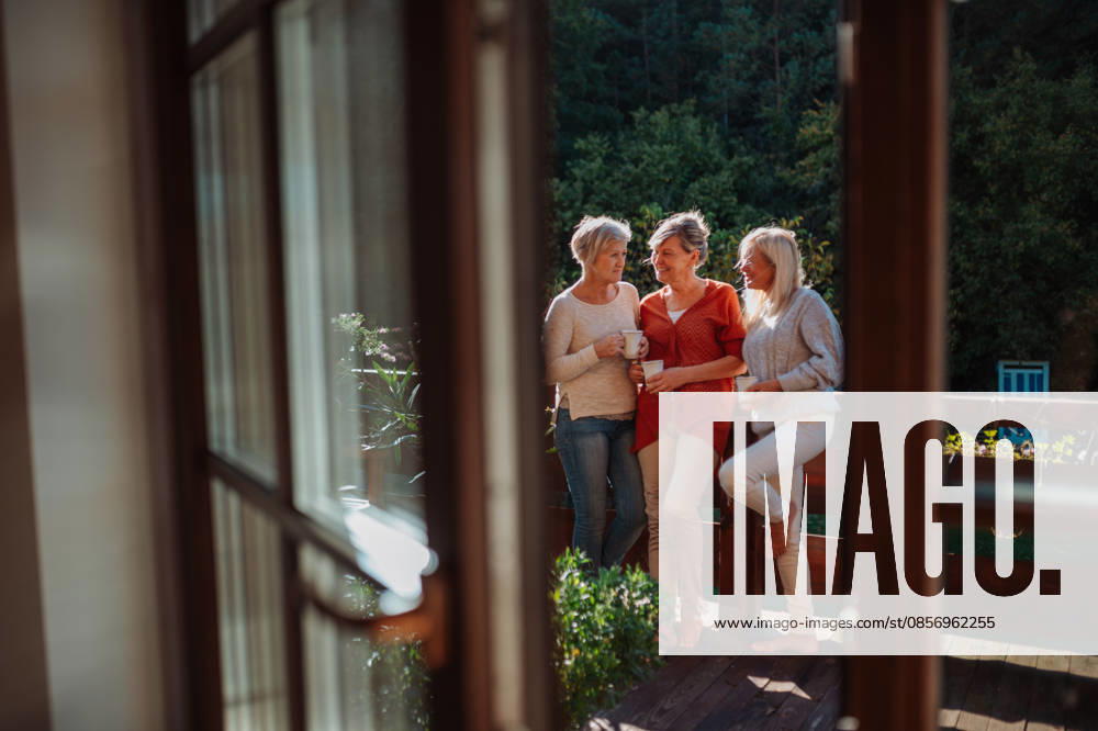 Senior female friends enjoying coffee together on cabin terrace getaway. Older female friends enjoying coffee together on cabin terrace getaway. model released