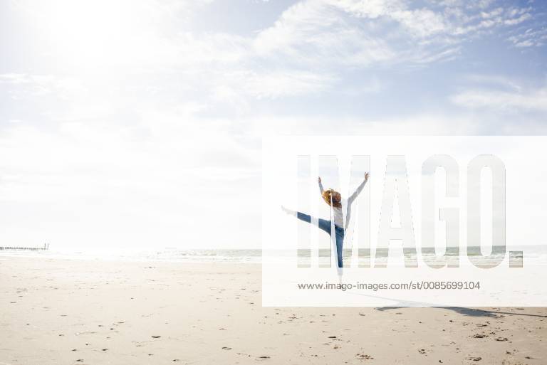 Happy woman having fun at the beach, jumping in the air model released Symbolfoto KNSF04245