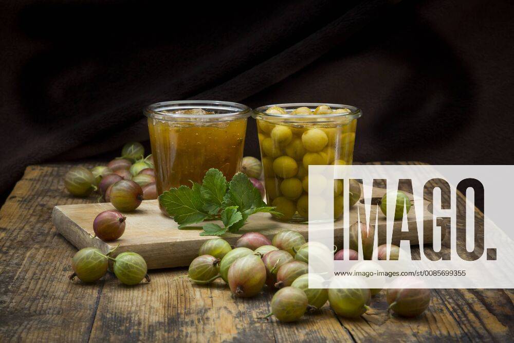 Jar of gooseberry jam, gooseberries and glass of preserved gooseberries on wood LVF06270