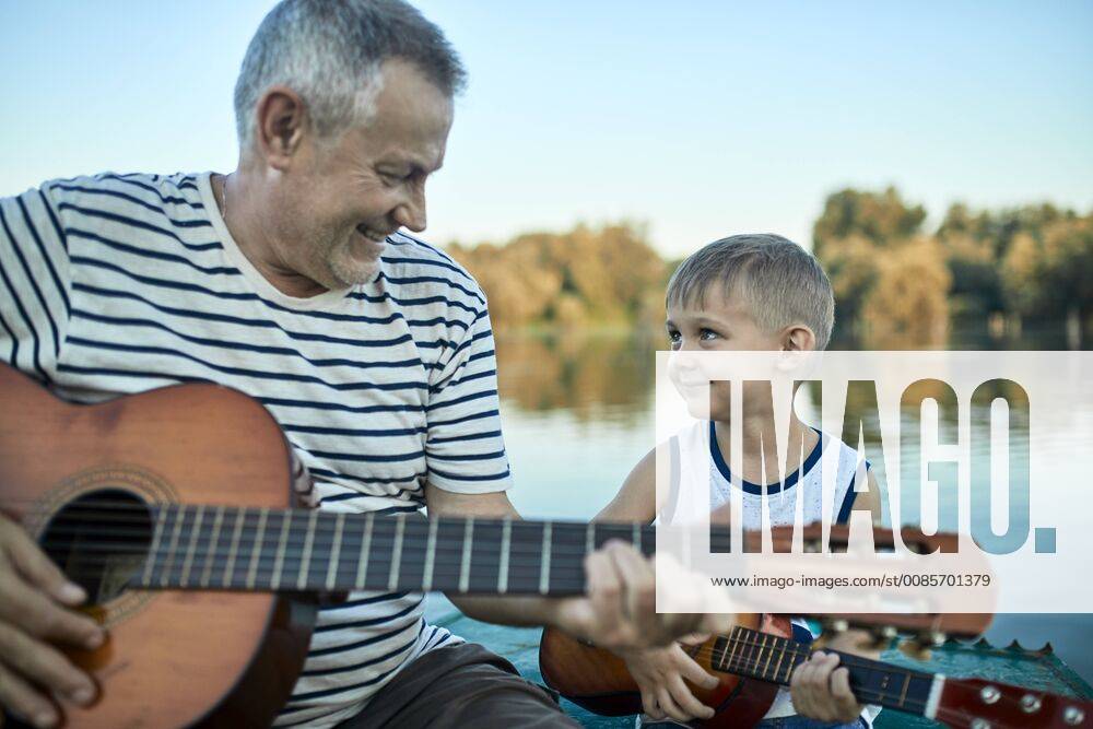 Grandfather teaching grandson playing guitar model released Symbolfoto ZEDF01498