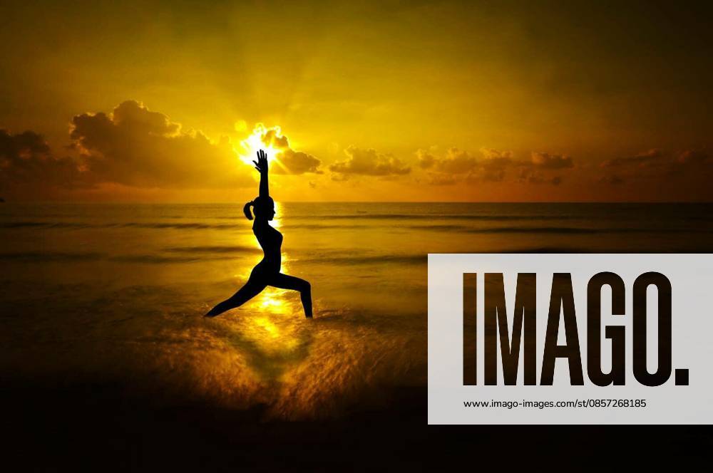 Silhouette of female doing yoga meditation during sunrise with natural golden sunlight at beach. model released Symbolfoto