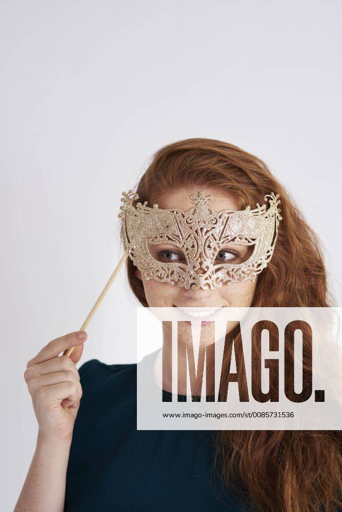 Portrait of smiling redheaded woman with masquerade mask model released Symbolfoto ABIF00884