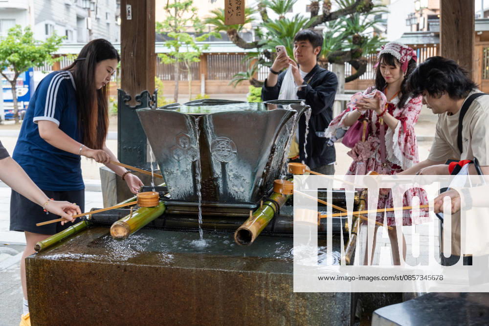 Fukuoka, Japan May 21, 2026: Visitors wash their hands at a traditional water basin at Kushida Shrine in Fukuoka, Japan. The scene depicts a typical purification ritual performed before entering the shrine and conveys Japanese culture, tradition, and religious customs.