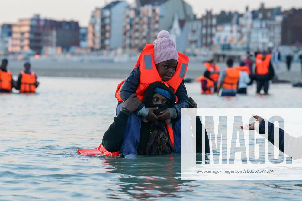Dunkirk, France. A migrants carrying a child, standing in the sea at the beach at Dunkirk, while attempting to cross the English Channel. More than 200,000 migrants have crossed the Channel in small boats since 2018. Dunkirk France - ZUMAl94_ 20260523_zaf_l94_025
