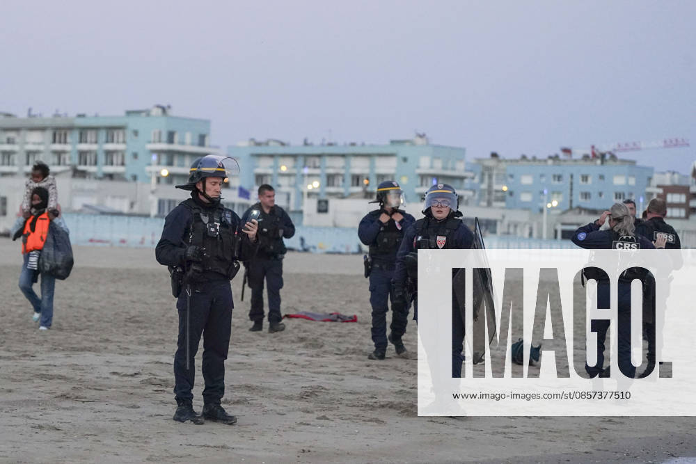 Dunkirk, France. Riot control police (CRS) watch on as migrants board an inflatable boat at the beach at Dunkirk, while attempting to cross the English Channel. More than 200,000 migrants have crossed the Channel in small boats since 2018. Dunkirk France - ZUMAl94_ 20260523_zaf_l94_066