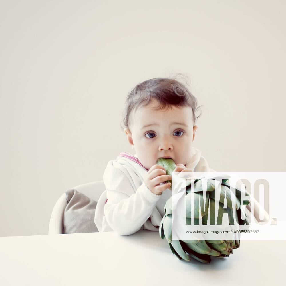Infant biting fresh artichoke