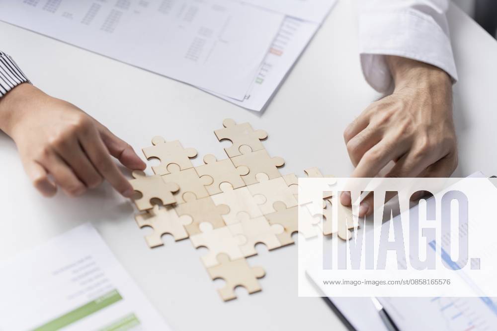 Geschäftsmannshände beim Zusammensetzen von Puzzleteilen mit Team Building Join Together und Business Collaboration Concept im Büro Businessman hands putting together puzzle pieces with Team Building Join Together and Business Collaboration Concept in the office