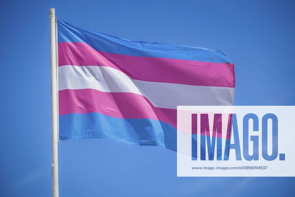 Pastellfarbene Transflaggen wehen auf einer Transgender Pride Flagge am Himmel von Lissabon, Portugal, für LGBT Gleichheit, fotografiert mit starker Hintergrundbeleuchtung Pastel trans flag colors wave on a transgender pride flag in the Lisbon, Portugal sky for LGBT equality, photographed with strong backlight
