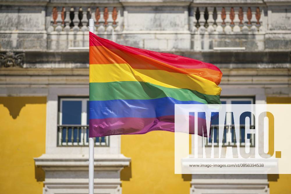 Die Farben des Regenbogens wehen auf einer traditionellen Pride Flagge am Himmel von Lissabon, Portugal, für LGBT Gleichheit, fotografiert vor dünnen Wolken Rainbow pride colors wave on a traditional pride flag in the Lisbon, Portugal sky for LGBT equality, photographed against wispy clouds