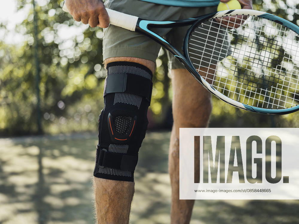 Tennis player wearing knee brace holding racket and ball outdoors model released, Symbolfoto, MFF10149