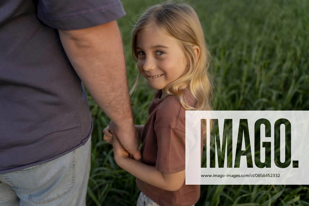 Father and daughter holding hands in green field smiling model released, Symbolfoto, OGSF00315