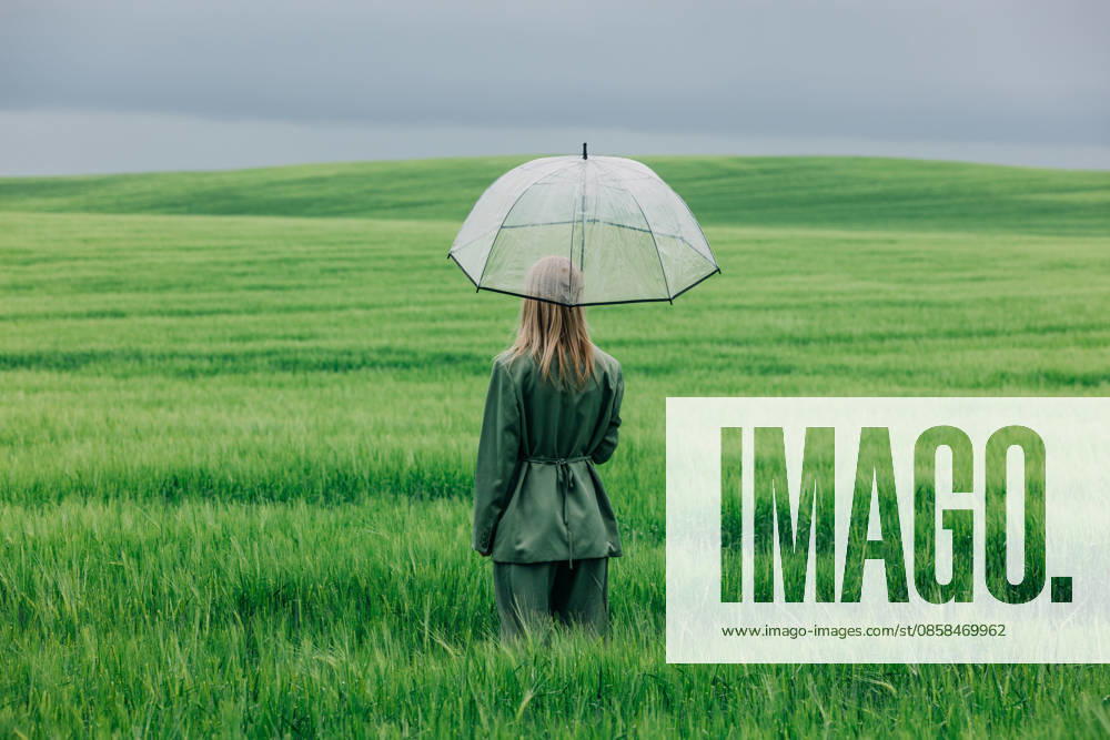 Woman standing in green wheat field with transparent umbrella in the rain model released, Symbolfoto, VSNF04975