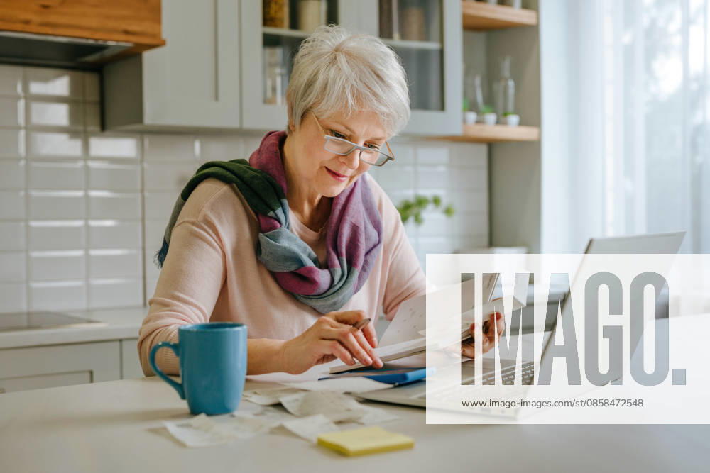 Woman calculating tax and budget with laptop in kitchen model released, Symbolfoto property released, YTF04873
