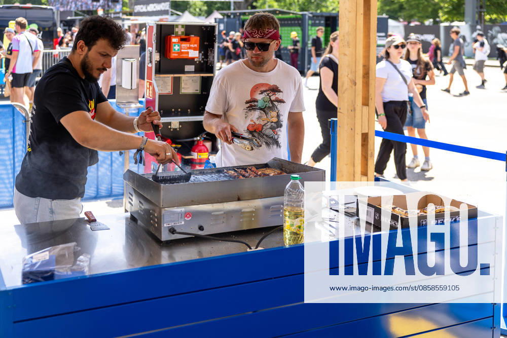 Rock im Park 2026 music festival, Nuremberg, 07 06 2026 Two employees grilling meat skewers at the Lidl BBQ station on the festival site Festival visitors can be seen in the background Nuremberg Bavaria Germany 20260607-286A8408-M4000