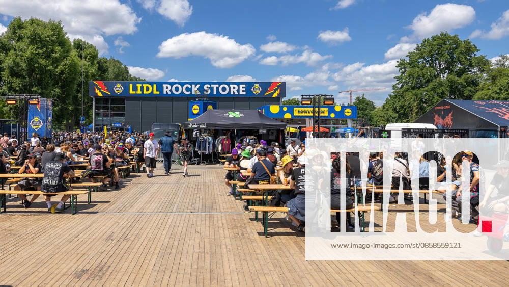 Music festival Rock im Park 2026, Nuremberg, 07 06 2026 Festival visitors sit at beer table sets on the grounds in sunny weather In the background the Lidl Rock Store with merchandising stands and other sales tents Nuremberg Bavaria Germany 20260607-286A8422-M4000
