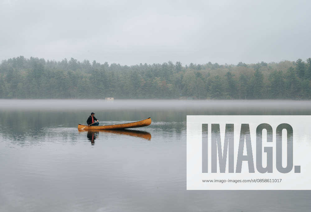 Man paddling a canoe on a still foggy lake Buck Lake, Ontario, Canada CR_DOHO260604G-2040774-01 ,model released, Symbolfoto