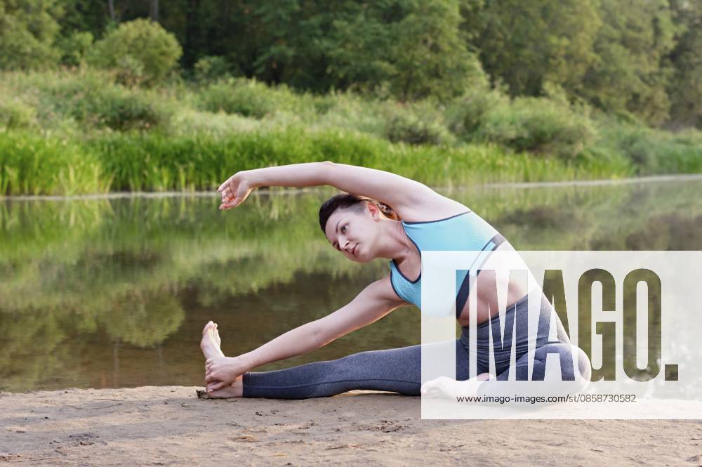 Ein junges Mädchen praktiziert Yoga auf dem See im Park. Nahaufnahme A young girl practices yoga on the lake in the park. Close-up