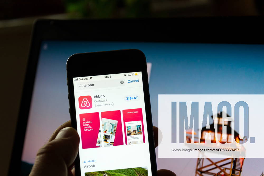 PRAG, TSCHECHISCHE REPUBLIK ? 21. NOVEMBER 2018: Das Logo des Unternehmens Airbnb auf dem Bildschirm einer Smartphone-App mit der Homepage im Hintergrund am 21. November 2018 in Prag, Tschechische Republik. PRAGUE, CZECH REPUBLIC - NOVEMBER 21 2018: Airbnb company logo on mobile app phone screen with internet homepage in background on November 21, 2018 in Prague, Czech republic. (License=RM)