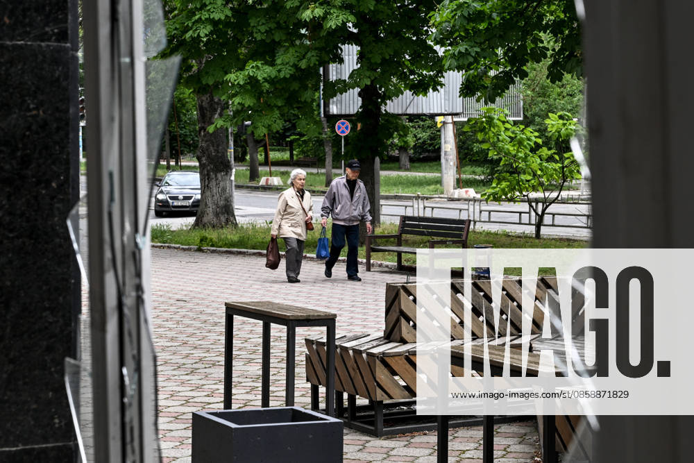 Lone pedestrians are seen through a shattered storefront window in the red zone of the frontline city of Kherson, the area considered the most dangerous due to constant Russian attacks, Kherson, Ukraine, on June 3, 2026. The Russian army attacks the city daily with FPV drones and other unmanned aerial vehicles, deliberately terrorizing civilians. Russian forces conduct hunts for local residents, tracking them with FPV drones and dropping explosives. Police officers, medics, public transport, and urban infrastructure are also targeted. Based on the intensity of attacks, Kherson is informally divided into yellow and red zones, with the red zone subjected to continuous shelling and drone strikes. Anti-drone netting has been installed