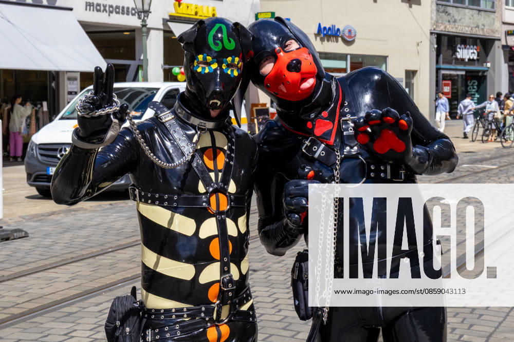 Augsburg, Bavaria, Germany June 13, 2026: Participants carrying rainbow flags and wearing colorful costumes take part in Christopher Street Day (CSD) in Augsburg. The parade through the city center promotes the rights of LGBTQ+ people as well as social diversity and tolerance. Two participants in latex costumes and puppy play masks pose