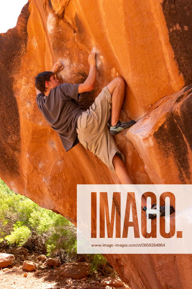 A young male climber bouldering on the Chaos Boulder, Big Bend Bouldering Area near Moab, Utah. Moab Big Bend Bouldering Area Utah United States