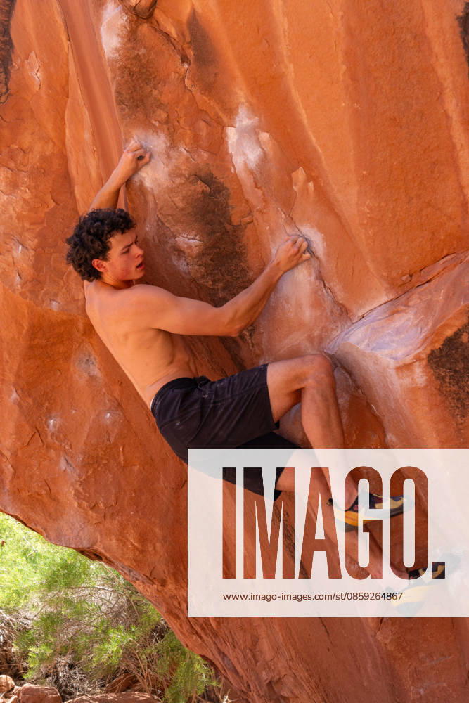 A young male climber bouldering on the Chaos Boulder, Big Bend Bouldering Area near Moab, Utah. Moab Big Bend Bouldering Area Utah United States