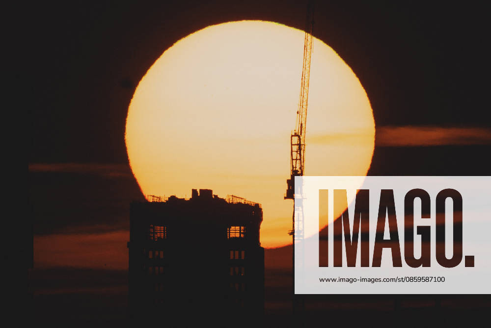 The setting sun is visible behind a new building with a crane in Berlin, June 19, 2026. A heat wave is currently affecting all of Germany. Berlin, Germany,detected_source_language