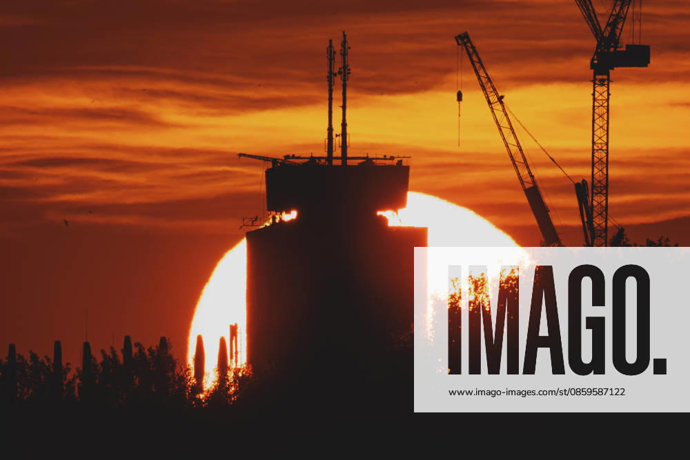 The setting sun is visible behind a new building with a crane in Berlin, June 19, 2026. A heat wave is currently affecting all of Germany. Berlin, Germany,detected_source_language