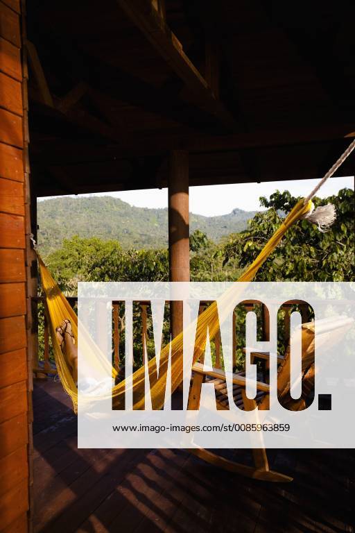 A person lays on a yellow hammok next to a chair at the deck of a cabin in Finca Argovia, Chiapas, Mexico., Chiapas Mexico model released Symbolfoto