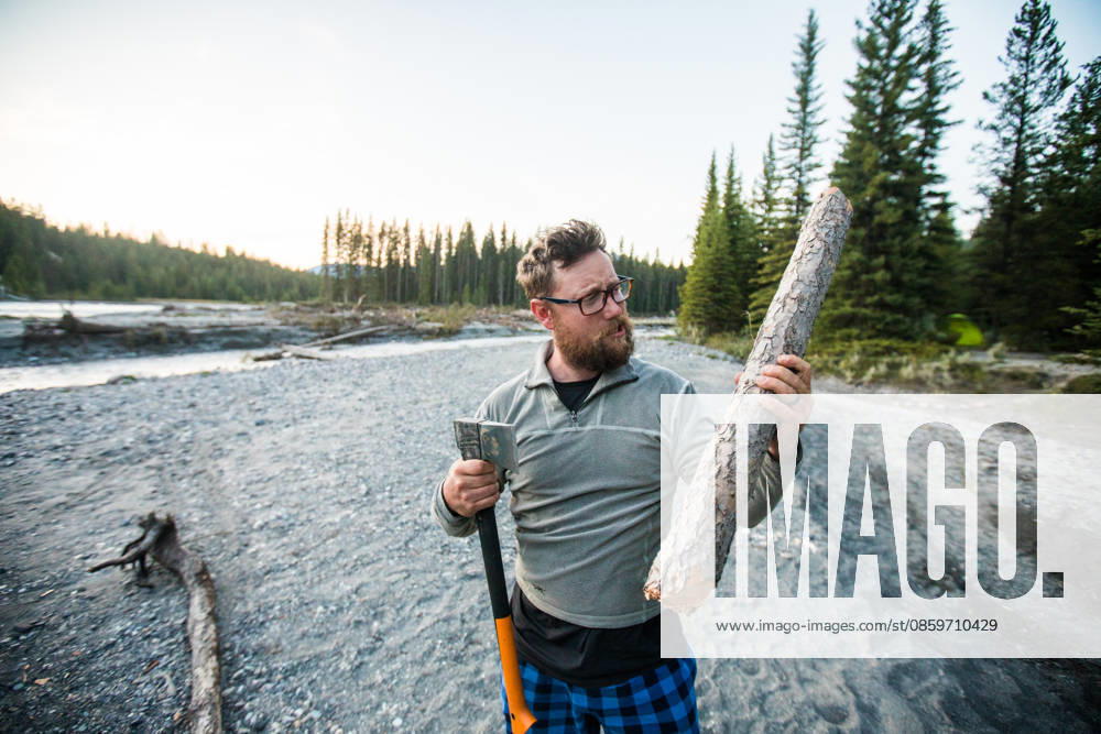 Man with an axe holding a log for firewood Canal Flats, British Columbia, Canada CR_JDIP260620C4-2054948-01 ,model released, Symbolfoto