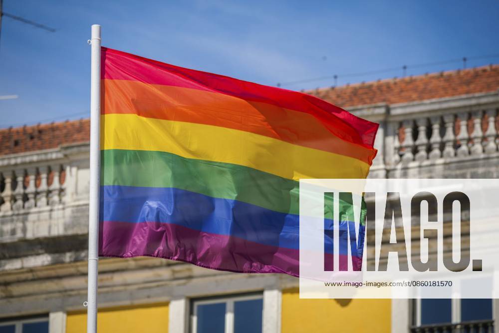 Die Farben des Regenbogens wehen auf einer traditionellen Pride Flagge am Himmel von Lissabon, Portugal, für LGBT Gleichheit, fotografiert bei warmem Tageslicht Rainbow pride colors wave on a traditional pride flag in the Lisbon, Portugal sky for LGBT equality, photographed in warm daylight